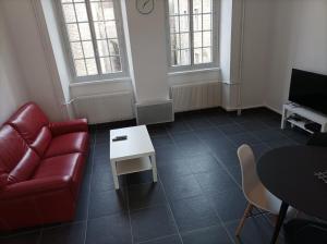 uma sala de estar com um sofá vermelho e uma mesa em O'Couvent - Appartement 77 m2 - 2 chambres - A321 em Salins-les-Bains