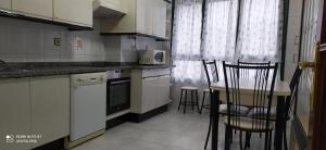 a kitchen with white cabinets and a table and chairs at Apartamentos xistra in Cangas del Narcea