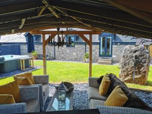 a patio with couches and a table and a rock at Pheasants Retreat with Hot Tub and Fire Pit in Trefnant