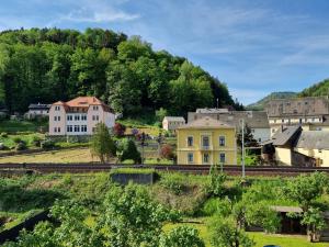 a town with a yellow house and train tracks at Ferienappartements Elbaussicht - Krippen in Bad Schandau