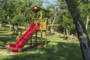 un parque infantil con un tobogán rojo en un parque en Park Hotel La Pineta, en Mulazzo