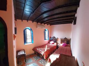 a bedroom with a bed and two windows at Dar Zman in Chefchaouen