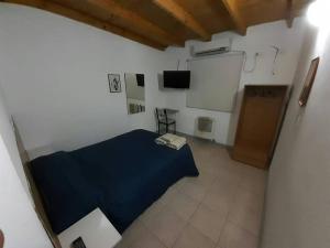 um quarto com uma cama azul e uma parede branca em Hotel Mitre em Chivilcoy