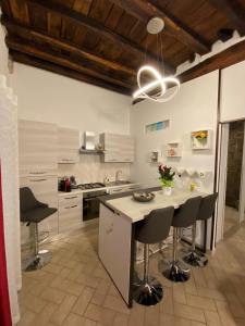 una cocina con armarios blancos y una isla con taburetes. en Casa medievale Il Rifugio di Olimpia en Viterbo