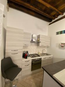 uma cozinha com armários brancos e uma cadeira em Casa medievale Il Rifugio di Olimpia em Viterbo