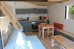 een kamer met een keuken, een tafel en een bank bij Maison Ti Havre avec jardin privé dans village de pêcheurs à Brem sur mer ! in Brem-Sur-Mer