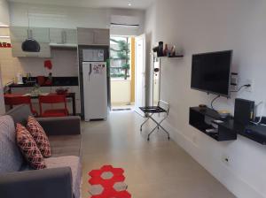 uma sala de estar com um sofá e uma televisão na parede em Charmoso Studio Leblon no Rio de Janeiro