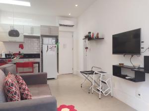 a living room with a couch and a tv on a wall at Charmoso Studio Leblon in Rio de Janeiro