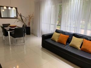 a living room with a black couch and a table at Green Park 2 Ambientes con Balcón Vista Bosque o Laguna con Parrillero in Punta del Este