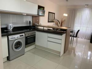 a kitchen with a washing machine and a dishwasher at Green Park 2 Ambientes con Balcón Vista Bosque o Laguna con Parrillero in Punta del Este