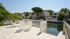 un patio con sillas blancas junto a una piscina en Casa Fluvia, en Empuriabrava