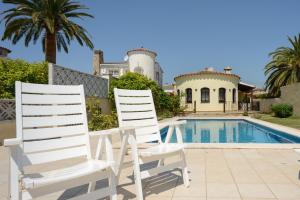 two white chairs sitting next to a swimming pool at Casa Fluvia in Empuriabrava