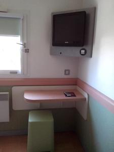 a room with a desk with a tv on the wall at ibis budget Poitiers Sud in Poitiers