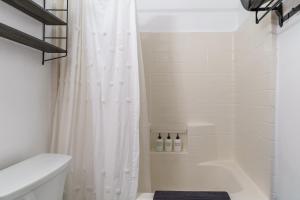 ein Bad mit einer Dusche mit einem weißen Duschvorhang in der Unterkunft Desert Twilight 29 - Hot Tub & EV Charger in Twentynine Palms