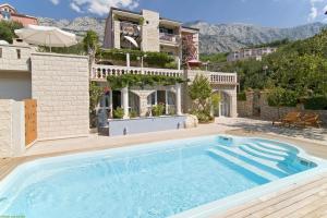 an outdoor swimming pool in front of a house at Villa Bougenvilia Tomas in Tučepi