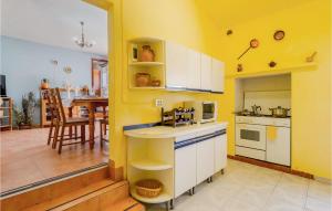 a kitchen with yellow walls and white cabinets at Awesome Home In Cortegana With Outdoor Swimming Pool in Cortegana