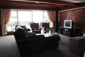 uma sala de estar com sofás e uma televisão e janelas em Sunnyridge Lodge em East London
