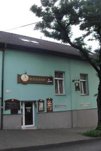 ein blaues Gebäude mit einem Baum davor in der Unterkunft Restaurant Švejk a Pension Brno in Brünn