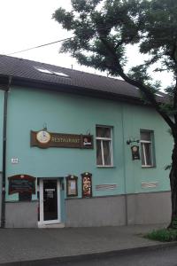 niebieski budynek z drzewem przed nim w obiekcie Restaurant Švejk a Pension Brno w mieście Brno