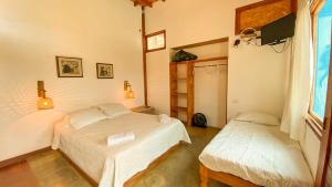 a bedroom with two beds and a tv on the wall at Terrazas Iguana in Máncora +29 photos