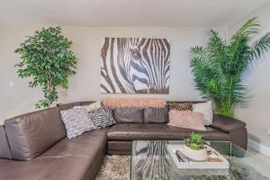 ein Wohnzimmer mit einem braunen Ledersofa und zwei Pflanzen in der Unterkunft Luxury Holistic Oasis by Bayshore/Hyde Park/SoHo in Tampa