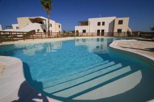 - une piscine d'eau bleue en face d'un bâtiment dans l'établissement Le Casuzze del Residence Lido Burrone, à Favignana