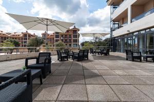 a patio with benches and umbrellas on a building at Hotel Viadero in Noja