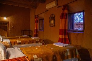 a room with three beds and a window at Riad Du Sud in Tamsahelt