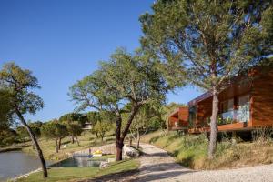 a house on the side of a river with trees at Herdade do Moinho Novo in Canha