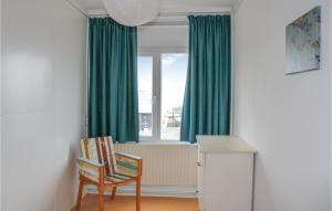 a room with a chair and a window with green curtains at De Tuimelaar in Bergen aan Zee