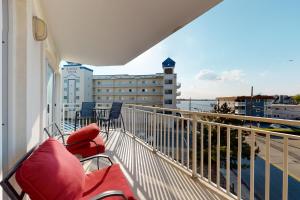 balcón con sillas rojas y vistas al agua en Bahia Vista II 305 en Ocean City