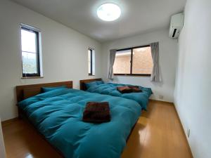2 blaue Betten in einem Zimmer mit 2 Fenstern in der Unterkunft Angel Resort Karuizawa in Karuizawa