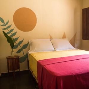 a bedroom with a bed with a red and yellow blanket at Pousada Canto Feliz in Serra do Cipo