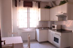 a kitchen with white cabinets and a microwave at A Traíña in Cambados