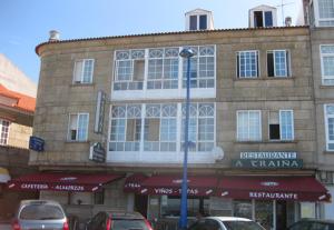 un edificio de ladrillo con coches estacionados frente a él en A Traíña, en Cambados