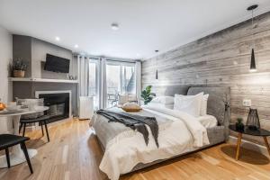 a bedroom with a large bed and a wooden wall at Studio LIV203 by Gestion ELITE in Mont-Tremblant