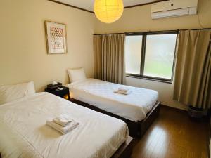 una camera d'albergo con due letti e una finestra di Shiki Homes HARU a Kyoto