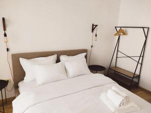 een wit bed met witte lakens en kussens bij Vista City Apartment in Podgorica +13 foto's