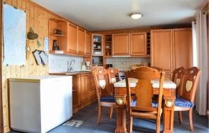 a kitchen with a wooden table and chairs and a white refrigerator at 2 Bedroom Amazing Apartment In S-4275 Svelandsvik in Sæveland