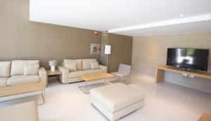 a living room with white furniture and a flat screen tv at M.A. Hotel Sevilla Congresos in Seville
