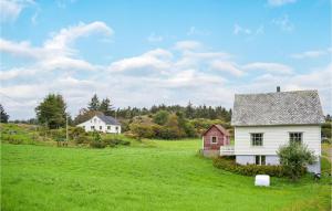 una casa blanca en un campo verde con casas en Amazing Home In Urangsvg With House A Panoramic View, en Bømlo