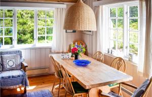 a dining room with a wooden table and windows at Gorgeous Home In Reksteren With Kitchen in Klinkholmen