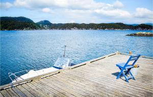 a dock with a blue chair and a boat on the water at Gorgeous Home In Reksteren With Kitchen in Klinkholmen +22 photos