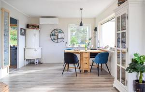 a kitchen with a wooden table and blue chairs at Beach Front Home In Bvgen With House Sea View in Bøvågen