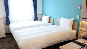 two beds in a small room with a window at Toyoko Inn Fujisan Otsuki-eki in Ōtsuki