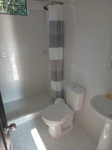 a white bathroom with a toilet and a sink at Hotel Villa Maritza in Melgar