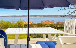 een witte picknicktafel met een parasol en uitzicht op het water bij 3 Bedroom Gorgeous Home In Bankeryd in Bankeryd