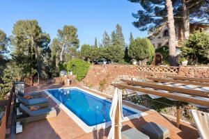 a swimming pool in a backyard with a stone wall at Luxury Villa El Turo in Castellví de Rosanés