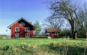 una casa roja en un campo con un árbol en Amazing Home In Gusum With 4 Bedrooms, Sauna And Wifi, en Gusum