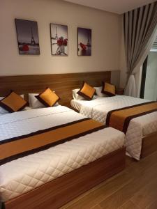 ein Hotelzimmer mit 2 Betten und Gemälden an der Wand in der Unterkunft Apec 5 sao TP.Tuy Hòa - View biển và view hồ bơi in Ðông Tác (1)